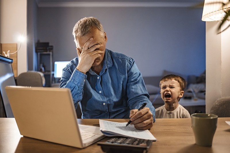 Stressed Man With his two years old son Working From Home